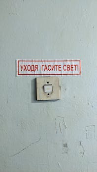 A close-up of an obsolete light switch with a Russian 'Turn Off the Light!' sign.