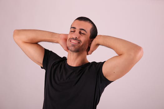 A smiling adult male relaxing in a casual black t-shirt against a plain studio backdrop.