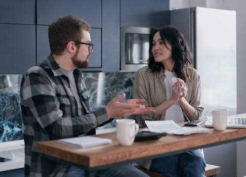 A young couple having a serious discussion about finances in their kitchen.