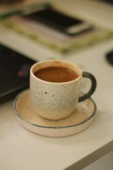 Close-up of a rustic ceramic cup filled with coffee on a desk, perfect for cozy work vibes.