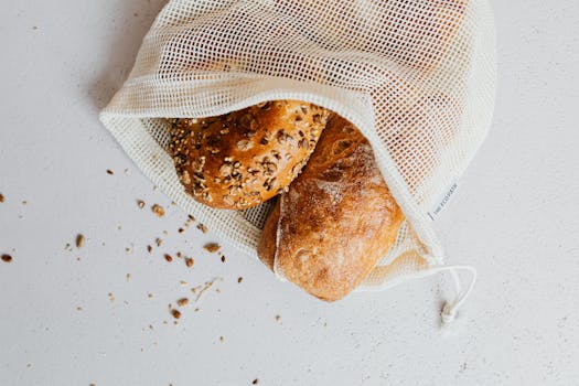 Close-up of artisan bread in a reusable mesh bag on a white surface, showcasing zero-waste lifestyle.