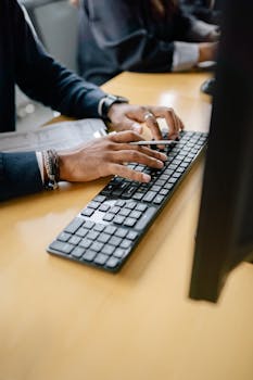 Close-up of hands typing on keyboard in an office setting, showcasing work professionalism.