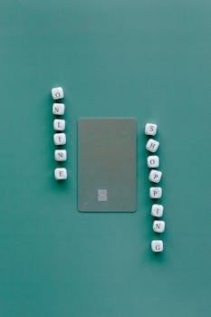 Flat lay with credit card surrounded by word "Online Shopping" on green backdrop.