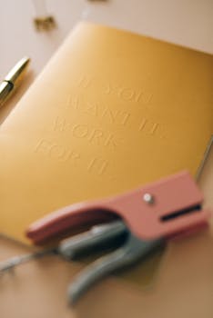 Gold notebook with motivational text alongside a puncher and pen on a desk.