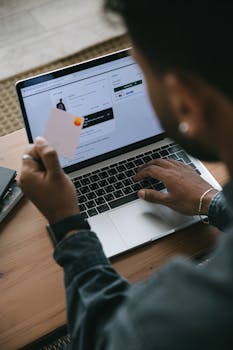 Person shopping online using a laptop and credit card.