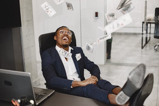 Relaxed businessman in office chair happily enjoying financial success with money falling around.