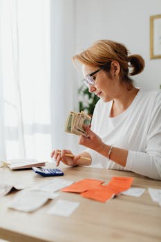 Woman counting cash and planning budget at indoor home office setting.